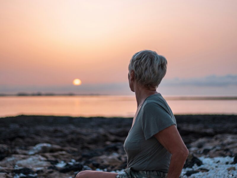 menopausal woman finding comfort and rest at the beach sunset