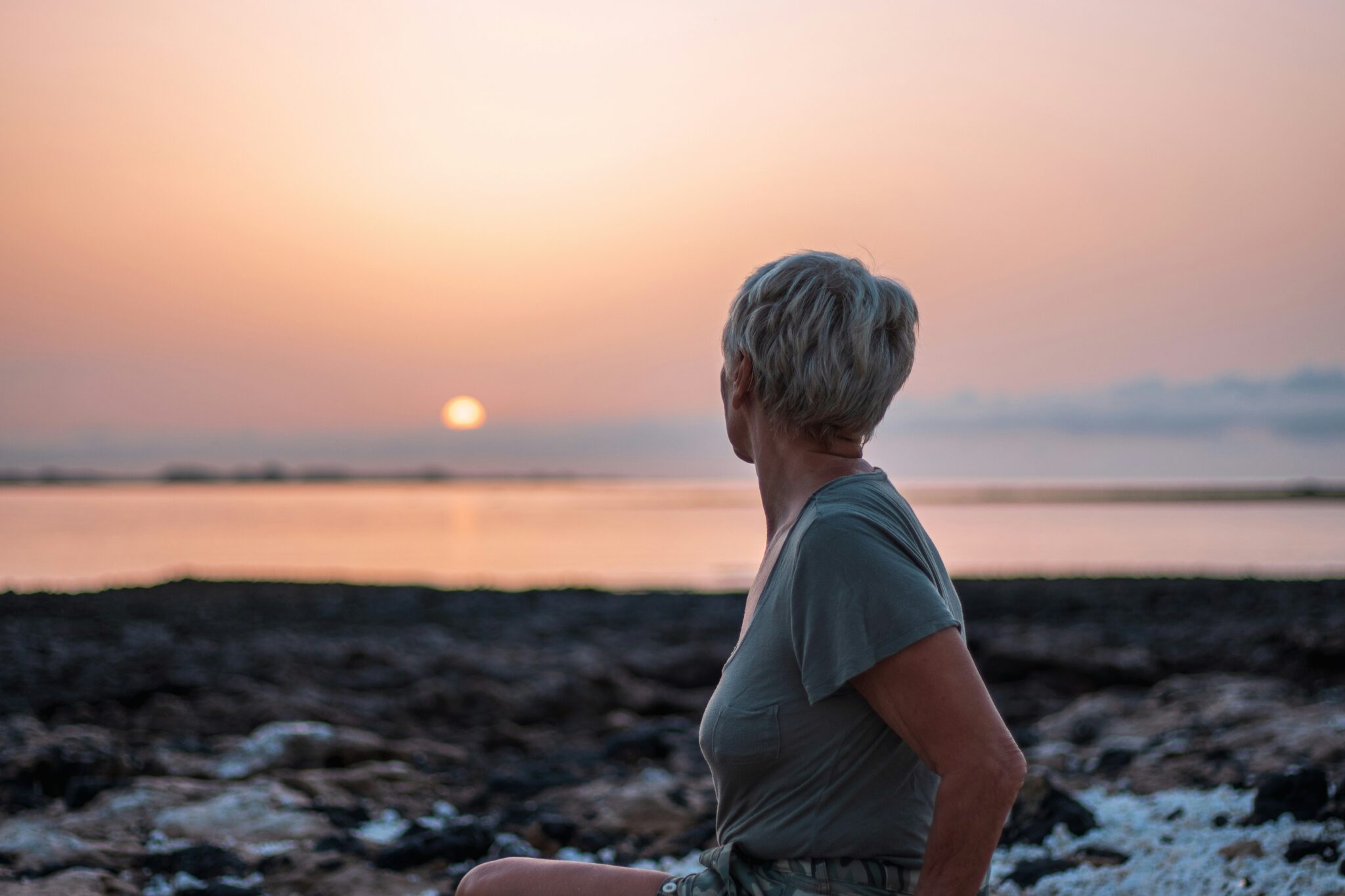 menopausal woman finding comfort and rest at the beach sunset